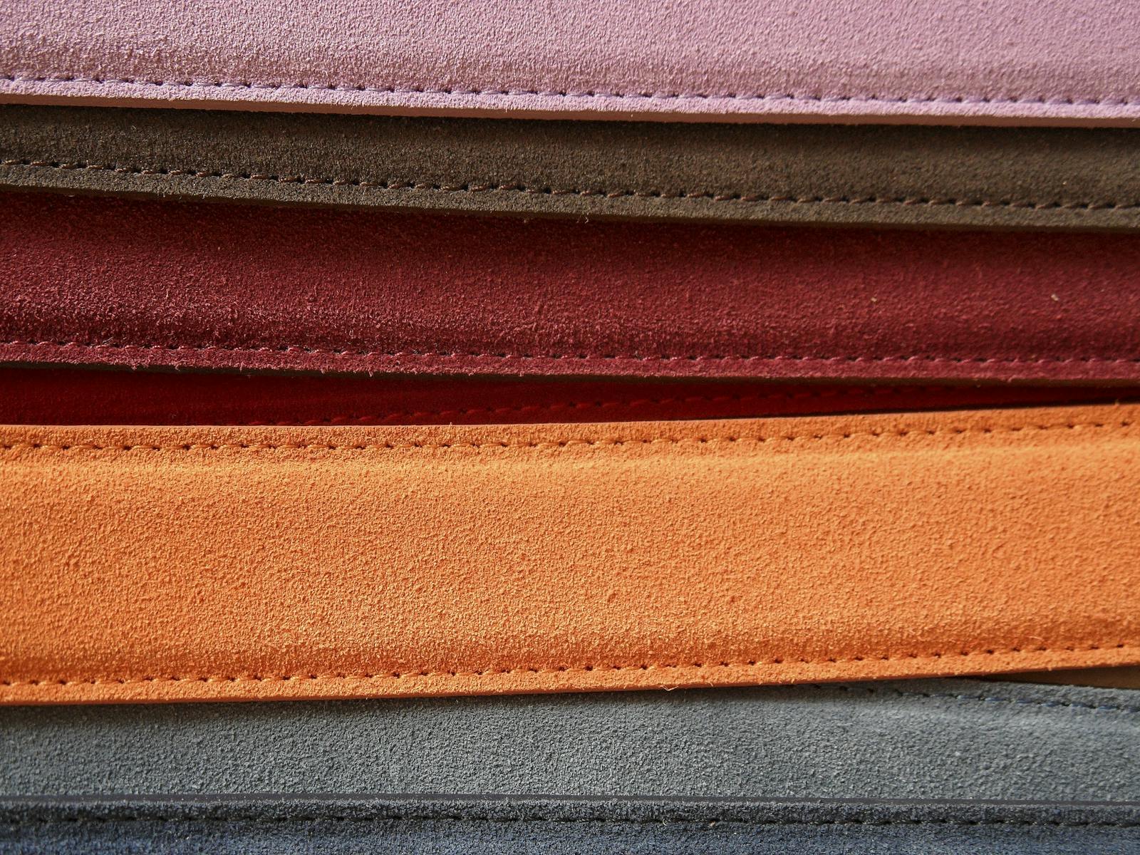 A row of finished leather belts in warm tones